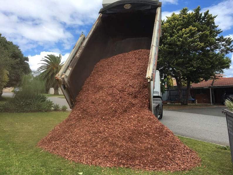 The Benefits of Mulching, iage of a truck dumping mulch in a garden